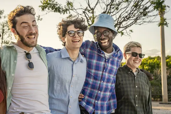 Sahici ve samimi bir portre dört mutlu, çeşitli genç adam açık havada birlikte gülüyor, güneşli bir günde gerçek bir dostluk ve neşe paylaşıyorlar..