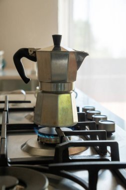 Klasik İtalyan moka demliği. Gaz ocağında taze espresso demliyor. Mavi bir alev, modern bir ev mutfağında geleneksel kahve makinesini ısıtıyor.