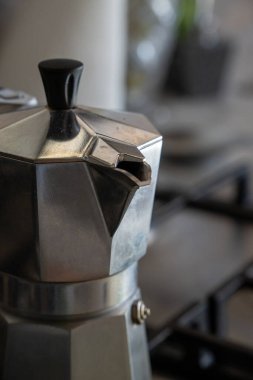 Klasik İtalyan moka demliğinin detaylı bir yakın çekimi, ikonik bir soba espresso makinesi, bir ev mutfağında bir gaz sobasının üzerinde oturuyor geleneği ve tasarımı temsil ediyor.