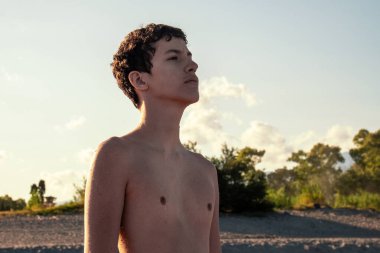 Umut dolu ve kararlı genç bir çocuk, güzel bir altın saat gün batımında gökyüzüne bakar. Gelecek, hırs ve gençlik potansiyelini temsil eder.