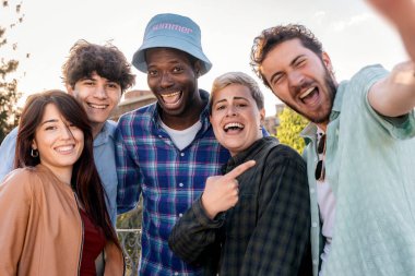 Heyecanlı bir grup arkadaş yaz günü dışarıda selfie çekiyorlar. Toplum kavramı, neşe ve gerçek arkadaşlık..