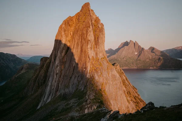 Yazın Lofoten adalarındaki ikonik kırmızı kulübe manzarası, karamsar sisli hava, ön planda yabani çiçekler.