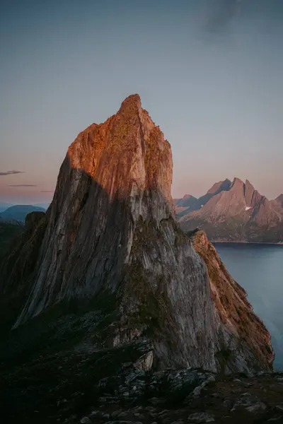 Yazın Lofoten adalarındaki ikonik kırmızı kulübe manzarası, karamsar sisli hava, ön planda yabani çiçekler.