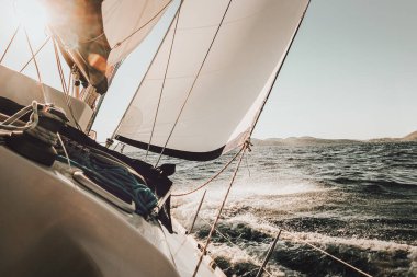 Denizde bir yat, günbatımı yelkenli yarışı. Eğik tekne okyanusta yüzüyor.