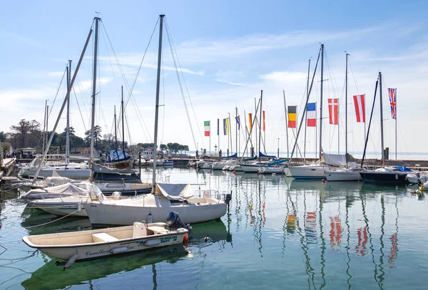 stock image Bardolino, Lake Garda, Italy - 29 March 2023 Sailing boats and flags of european countries at harbour of Bardolino.