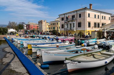 Bardolino, Garda Gölü, İtalya - 23 Mart 2024 Bardolino Limanı 'ndaki renkli balıkçı tekneleri ve evler. 
