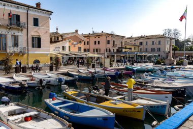 Bardolino, Lake Garda, Italy - 23 March 2024 Colorful fishing boats and houses at harbour of Bardolino.  clipart