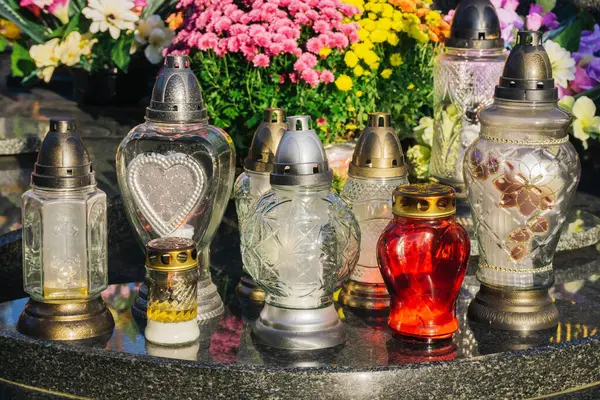 Katolik mezarlığı geçmişi. Azizler bayramı. Mezar mum ışığı. Mezarlıkta Cadılar Bayramı. Mermer mezardaki mezar mumları. Mezarları çiçeklerle süslemek.