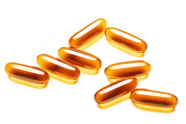 Altın yumuşak kapsüller beyaz arka planda sıralanmış. Parlak desenli saydam omega-3 balık yağı hapları. Sağlık, bağışıklık sistemi ve günlük refah için besin takviyelerinin yakın plan görüntüsü.
