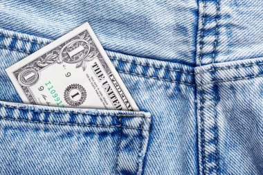Bir dolarlık kot pantolon. Para cepte. Para biriktirme fikri. Finans konsepti. Bütçe planlama sembolü. Denim dokusu yakın çekim. Güvenli depo. Gündelik para. Cep harçlığı ekonomisi. Basit finansal tema.