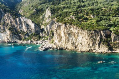 Ağaçlı kayalık sahil. Güzel manzara manzarası. Mavi deniz suyu. Güneşli yaz havası. Doğal uçurum kıyısı. Manzaralı seyahat yeri. Huzurlu bir tatil geçmişi var. Akdeniz doğası.