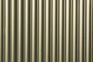 Dikey metalik borular. Tüp deseni tekrarlanıyor. Altın tonlarda endüstriyel doku. Kusursuz silindirik elementler. Modern duvar tasarımı. Mimarlık ve mühendislik kullanımı için temiz yüzey.