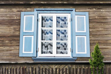 Küçük kır evindeki ahşap kırsal pencere. Klasik sarı boya duvarı. Dantel perdeli şeffaf cam pencere