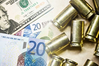Savaş geçmişinin bedeli. Euro ve dolar banknotları. Banknotların üzerindeki mermi kovanları. 