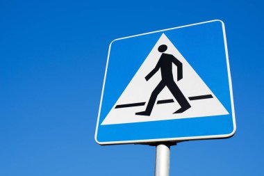 Yaya geçidi tabelası. Mavi gökyüzü boş kopyalama alanı. Üçgen yol işareti. Yürüyüş yolu uyarı sembolü. Yol geçmişinde güvenlik var. Caddede yaya geçidi. Hız yapma.