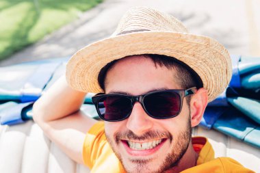 Küba 'da Cabriolet' e giderken kameraya bakarken gülümseyen hasır şapkalı ve güneş gözlüklü olumlu bir erkek turist.