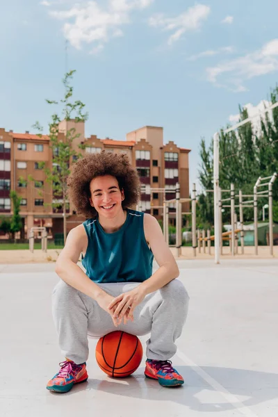 Улыбающийся Спортивный Мальчик Сидящий Баскетбольном Мяче Городской Площадке — стоковое фото