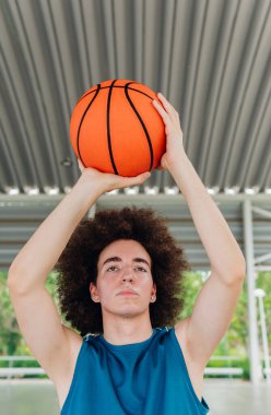 Şehir mahkemesinde basketbol topu atmaya hazır bir gencin fotokopi çekilen dikey portresi.