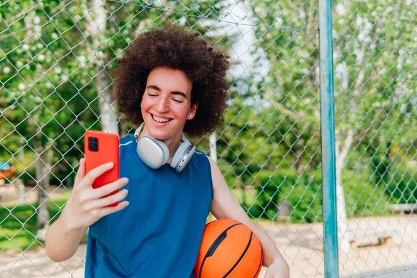 Jongen Met Behulp Van Telefoon Staand Met Een Basketbal Een — Stockfoto