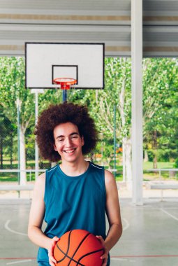 Basketbol sahasındaki neşeli bir çocuğun dikey portresi.