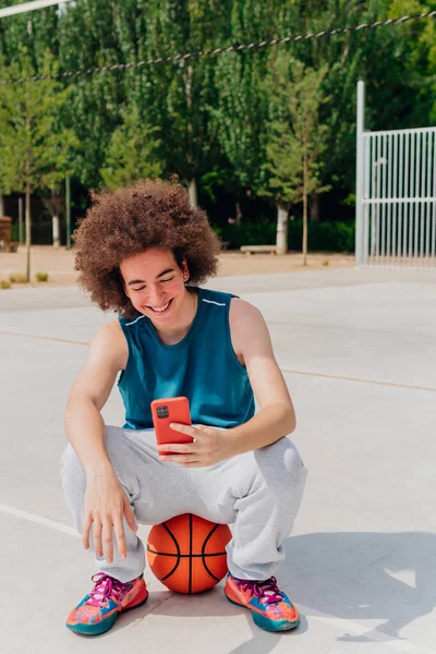 Sportif çocuk basketbol antrenmanından sonra, akıllı telefonuna ve sosyal ağlarına bakıyor..