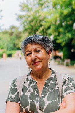 Açık havada gülümseyen olgun orta yaşlı bir kadın. 60 'lı yılların beyaz saçlı yaşlı kadını kameraya, portreye bakıyor..