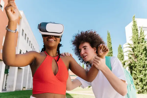 3d digital virtual technology. Education with modern gadgets and technologies. Happy smiling two positive friends, African girl and African boy, moving hands while trying VR glasses
