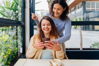 Anne, bir kafedeki masada yanan mumla kızına sürpriz yapıyor.