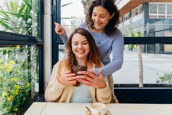 Anne, bir kafedeki masada yanan mumla kızına sürpriz yapıyor.