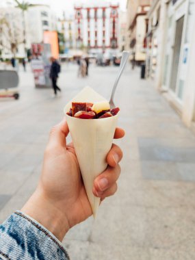 İspanya, Seville sokaklarında yürürken İber jambonu ve manchego peynirinin tadını çıkaran bir turist