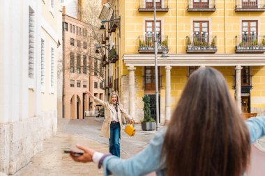 İki neşeli bayan arkadaş neşeyle yeniden bir araya geliyor. Resimli bir şehir caddesinde, bağlantılarının sıcaklığını kucaklıyor ve birlikte saf mutluluğu paylaşıyorlar.