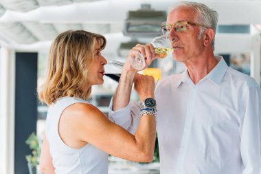 Olgun bir çift şık bir restoranda kırmızı ve beyaz şarabın tadını çıkarırken, birlikte sofistike ve samimi bir yemek deneyiminin tadını çıkarırken ebedi aşklarını kutluyorlar.