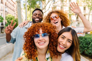 Dört neşeli çoklu etnik arkadaş şehirde bir günün tadını çıkarıyorlar. El kol hareketi yapıyorlar, gülümsüyorlar ve birlikte eğleniyorlar. Gençlik enerjilerini ve çeşitli arkadaşlıklarını gösteriyorlar.