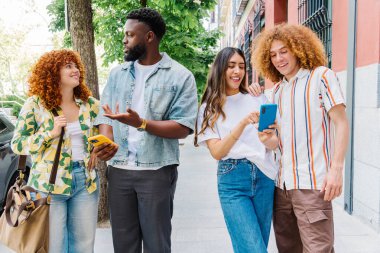 Aralarında öğrenci ve turistlerin de yer aldığı dört genç arkadaş, akıllı telefonlarını navigasyon, iletişim ve deneyim paylaşımı için kullanarak kentte birlikte yürüyüş yapıyorlar.