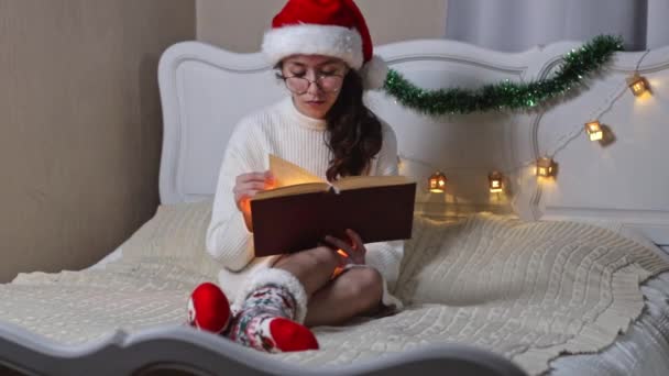 Schöne Kaukasische Teenagerin Mit Brille Und Weihnachtsmann Hut Liest Ein — Stockvideo