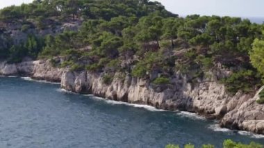Akdeniz körfezi olan kayalık bir dağın güzel panoramik manzarası ve Fransa 'nın güneyinde dalgalar, yan görüş, yavaş çekimde yakın çekim ve uzaklaşma.