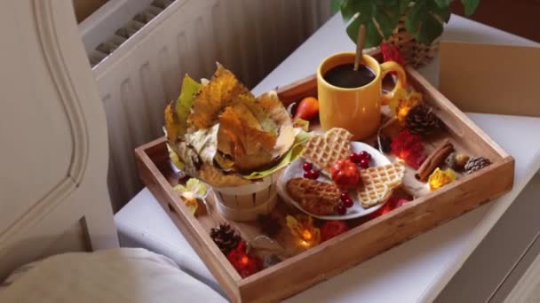 一个装有咖啡杯的木制盘子 茶托里放着松饼 篮子里放着一束白杨树叶 床头柜里放着秋天的装饰 旁边放着一张空的手工纸片 侧面看 动作缓慢 放大了 — 图库视频影像