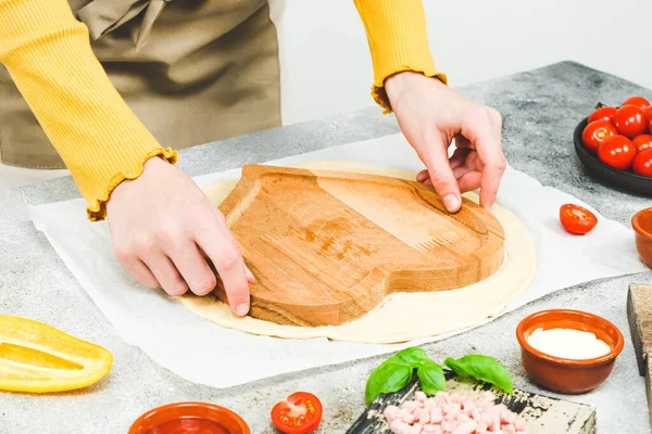 앞치마를 코카서스 소녀의 반죽을 발렌타인데이 피자를 모양의 반죽을 만들었습니다 테이블 — 스톡 사진
