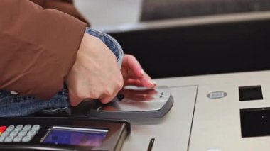 Kahverengi yağmurluklu güzel bir manikürlü beyaz kızın elleri mağazanın self-servis bölümünde manyetik etiketi yavaş çekimde, seçici bir odak noktasında kendi başlarına çıkartıp uzaklaşırlar..