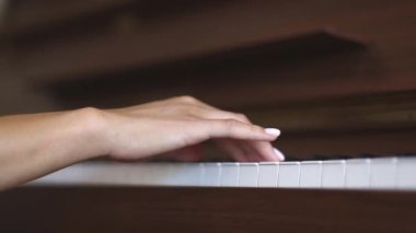Nazik beyaz manikürlü, piyano çalan beyaz tenli genç bir kadının eli, yavaş çekim ve derin saha görüntüsüyle yakın plan. Müzik konsepti, müzik dersi, müzik hobisi, müzik eğitimi..