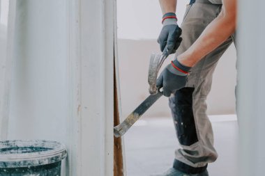 Gri tekstil eldivenli genç beyaz bir adamın elleri levye ve çekiç kullanarak eski ahşap çizgileri seçici bir odaklanma ile kapı aralığından kaldırıyor. İnşaat konsepti..
