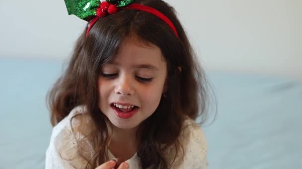 Красивая Маленькая Белая Девочка Хвостиком Голове Рождественском Костюме Сидит Кровати — стоковое видео