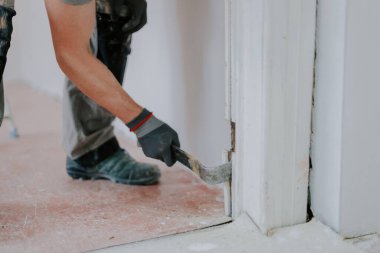 Gri tekstil eldivenli genç beyaz bir adamın elleri, levye kullanarak eski ahşap çizgileri kapı aralığından seçici bir odaklanma ile kapatıyor. İnşaat işi kavramı..