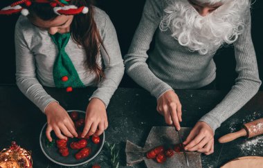 Noel Baba şapkalı, sakallı ve saç bantlı iki beyaz kız masada oturup pizza hazırlarken çok mutlular. Yaşam tarzı konsepti ve Noel hazırlığı.