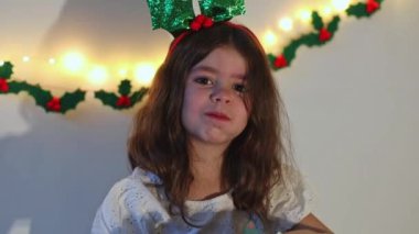 Kafkasyalı güzel esmer kız gülümseyerek yatakta oturuyor. Gelen takvimden çikolatalı şekeri yiyor. Yavaş çekimde yan çekimde..