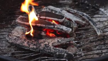 Ateşle yanan odun, az miktarda duman ve ızgarada uçan küller, yavaş çekimde yan görüntü. Barbekü pişirme konsepti.