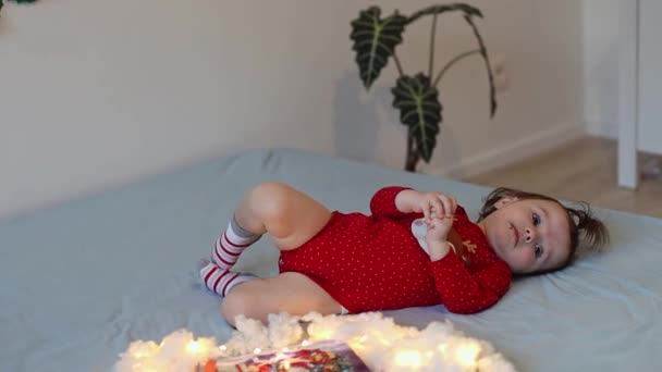 Egy Gyönyörű Kis Kaukázusi Kislány Lófarokkal Fején Karácsonyi Öltönyben Fekszik — Stock videók