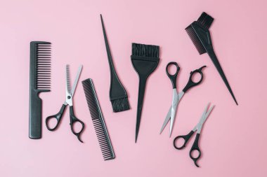 A set of hairdresser's tools from scissors,brushes and combs on a pink background,flat lay closeup. The concept of hairdressing, beauty salon, tools.