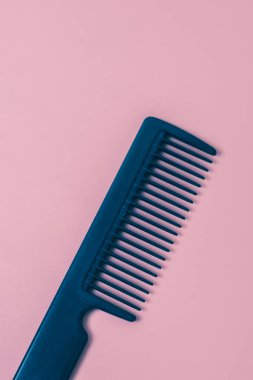 One black comb hairdresser on a pink background, flat lay close up. The concept of hairdressing, beauty salon, tools.