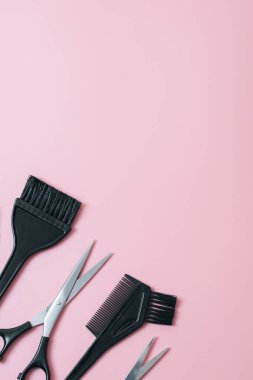 A set of hairdresser's tools from scissors,brushes and combs on a pink background with little copy space,flat lay close up. The concept of hairdressing, beauty salon, tools.